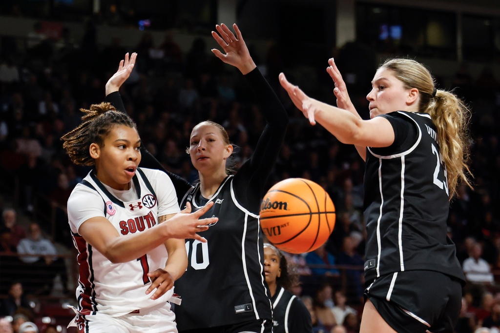 South Carolina guard Maddy McDaniel, left, passes against Providence forwards Audrey Shields and Ashley Dinges during the first half of an NCAA college basketball game in Columbia, S.C., Sunday, Dec. 28, 2025. (AP Photo/Nell Redmond)