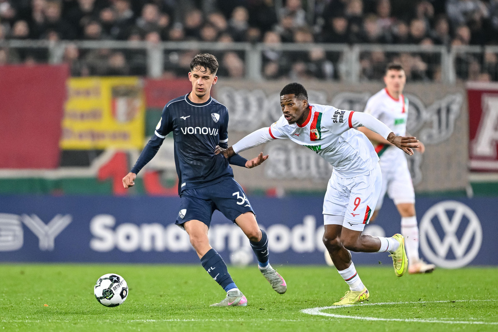 Augsburg's Samuel Essende, right, and Bochum's Cajetan Lenz, left, challenge for the ball during a German soccer cup second round match between FC Augsburg and VfL Bochum in Augsburg, Germany, Tuesday, Oct. 28, 2025. (Harry Langer/dpa via AP)