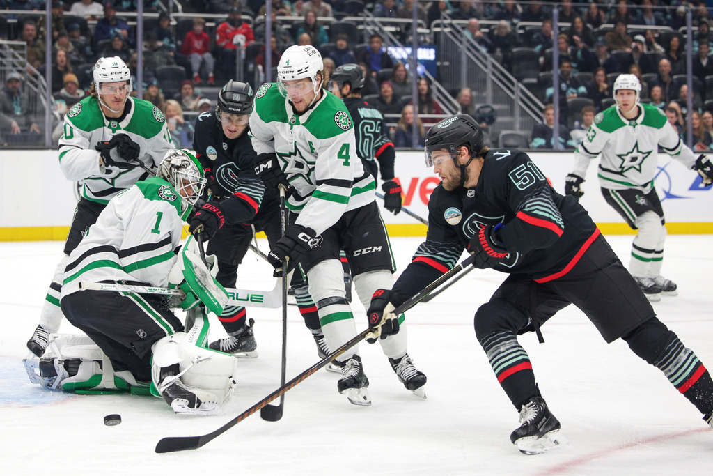 Seattle Kraken center Shane Wright (51) tries to score as Dallas Stars goalie Casey DeSmith (1) and defenseman Miro Heiskanen (4) defend during the first period of an NHL hockey game Wednesday, Nov. 26, 2025, in Seattle. (AP Photo/Jason Redmond)