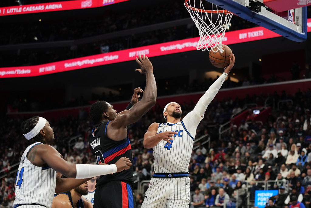 Orlando Magic guard Jalen Suggs, right, shoots against Detroit Pistons center Jalen Duren, center, as center Wendell Carter Jr. watches during the first half of an NBA Cup basketball game, Friday, Nov. 28, 2025, in Detroit. (AP Photo/Ryan Sun)