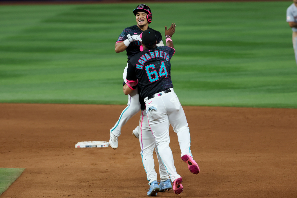 Miami Marlins' Javier Sanoja, top, celebrates with teammates Brian Navarreto (64) and Jakob Marsee, center, after hitting the winning RBI single during the ninth inning of a baseball game against the Washington Nationals, Friday, Aug. 21, 2026, in Miami. (AP Photo/David Santiago)