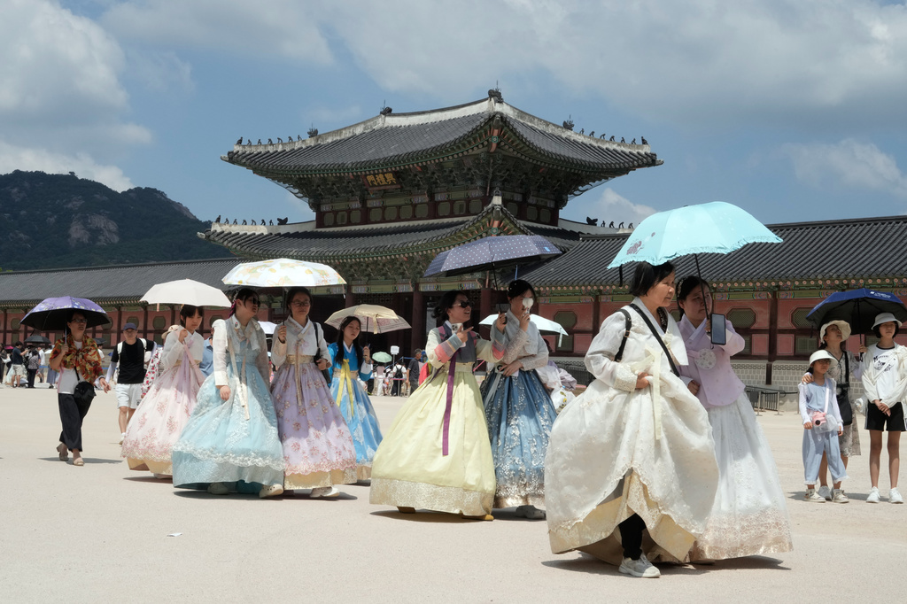 Visitors holding umbrellas to avoid sunshine leave the Gyeongbok Palace in Seoul, South Korea, Wednesday, Aug. 5, 2026. (AP Photo/Ahn Young-joon)