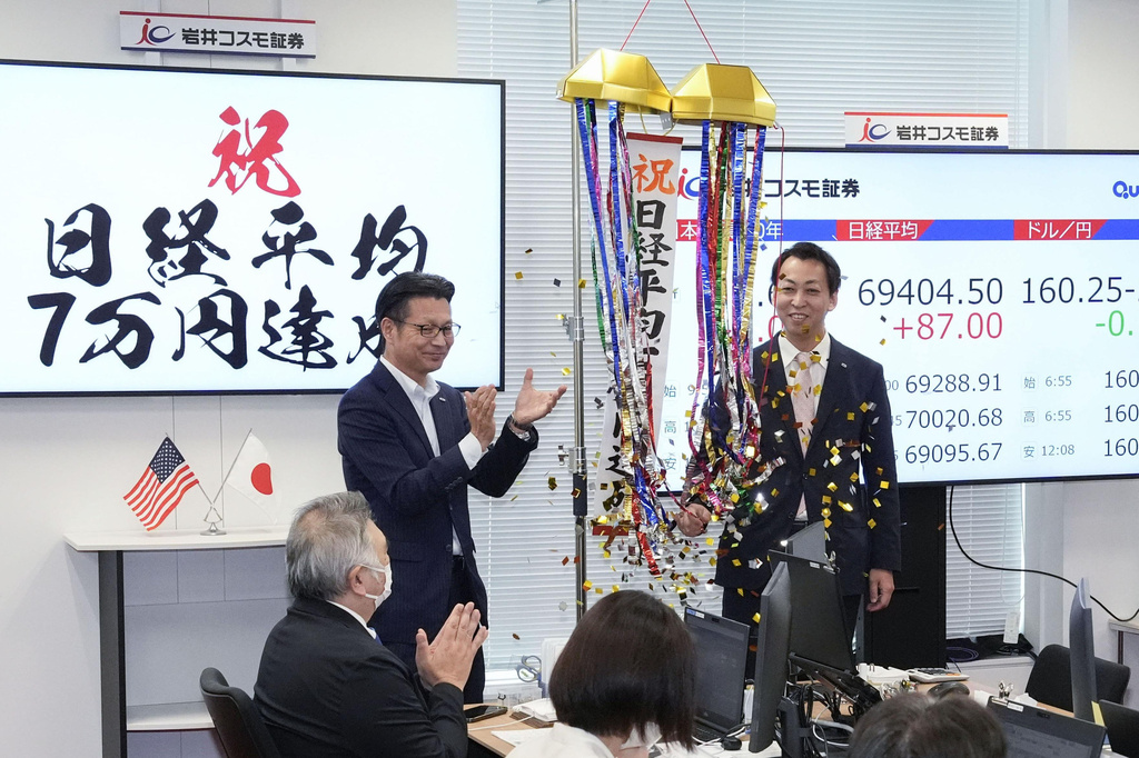 Employees of a securities company celebrate as Japan's benchmark Nikkei 225 topped 70,000 for the first time during trading hours in Tokyo Tuesday, June 16, 2026. A sign, left, reads "Congratulations. Nikkei index reached 70,000 yen." (Shinji Kouchi/Kyodo News via AP)