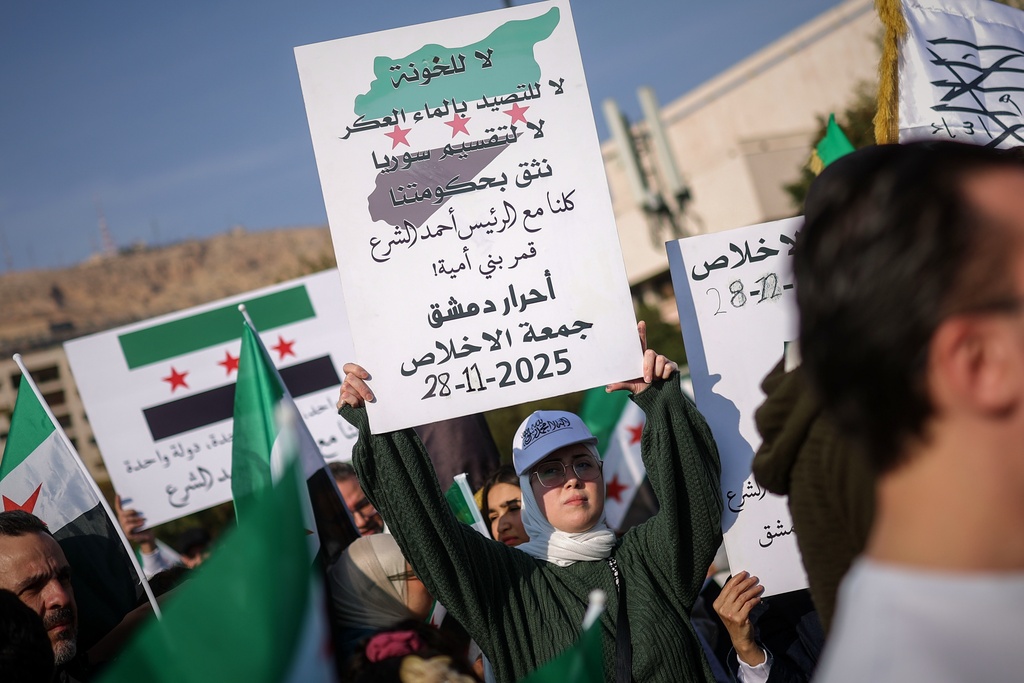 A woman holds a sign during a protest against an Israeli raid in the southern Syrian village of Beit Jin, in Damascus, Friday, Nov. 28, 2025. (AP Photo/Ghaith Alsayed)