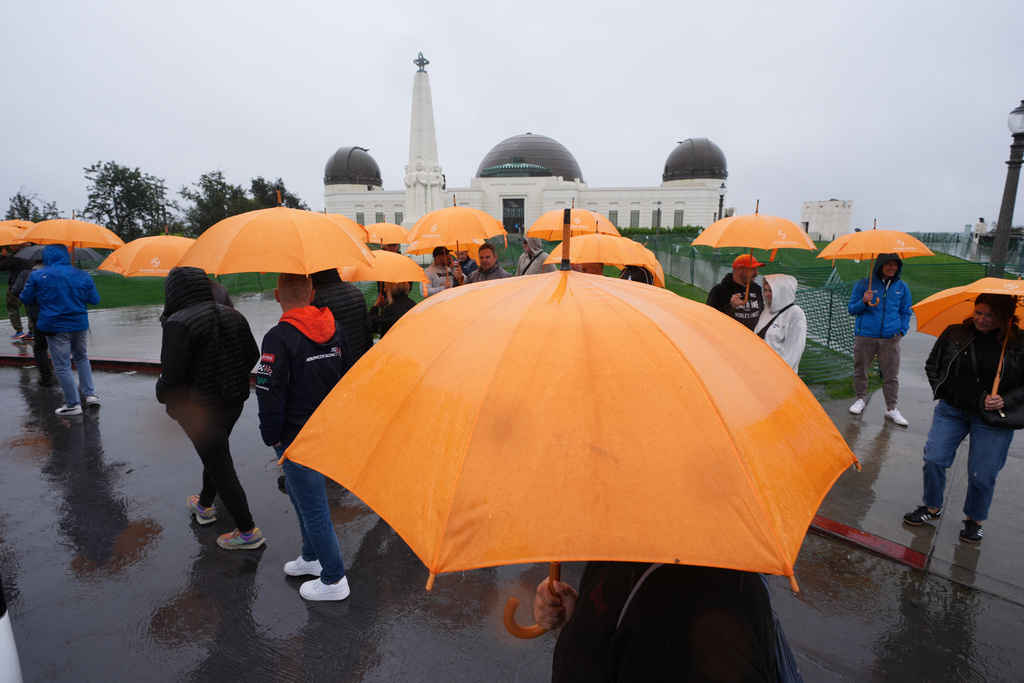 Tourists from Poland carry umbrellas as rain falls while visiting the Griffith Observatory Tuesday, Oct. 14, 2025, in Los Angeles. (AP Photo/Damian Dovarganes)