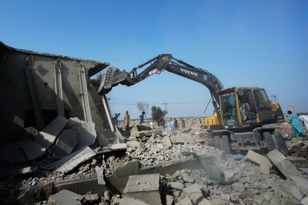 A hydraulic shovel demolish a structure during an operation against illegal settlement of Afghan refugees conducted by local government, on the outskirts of Karachi, Pakistan, Wednesday, Oct. 15, 2025. (AP Photo/Fareed Khan)