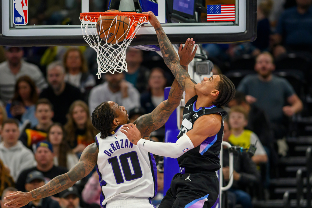 Utah Jazz guard Keyonte George, right, dunks the ball over Sacramento Kings guard DeMar DeRozan, left, during the first half of an NBA Cup basketball game Friday, Nov. 28, 2025, in Salt Lake City. (AP Photo/Tyler Tate)