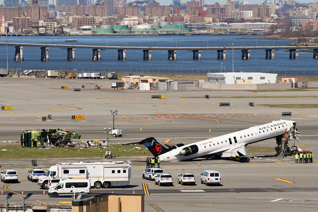 Aircraft maintenance workers arrive to inspect the wreckage of an Air Canada Express jet, Tuesday, March 24, 2026, just off the runway where it had collided with a Port Authority fire truck Sunday night at LaGuardia Airport in New York. (AP Photo/Yuki Iwamura)