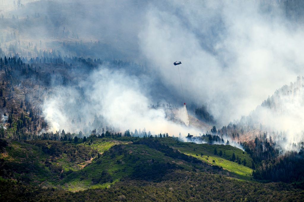 A helicopter drops water on the Cottonwood Fire burning near Beaver, Utah, on Saturday, June 27, 2026. (AP Photo/Noah Berger)