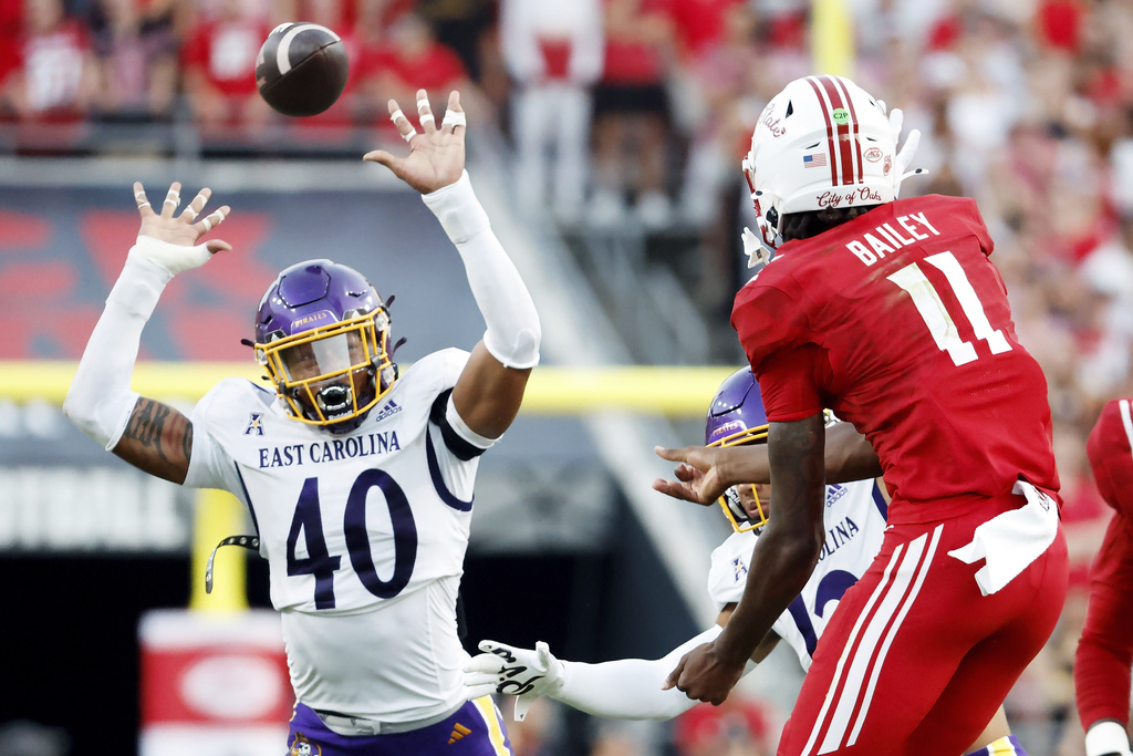North Carolina State quarterback CJ Bailey (11) throws the ball between the arms of East Carolina's Kendrick DuJour (40) during the first half of an NCAA college football game in Raleigh, N.C., Thursday, Aug. 28, 2025. (AP Photo/Karl DeBlaker)