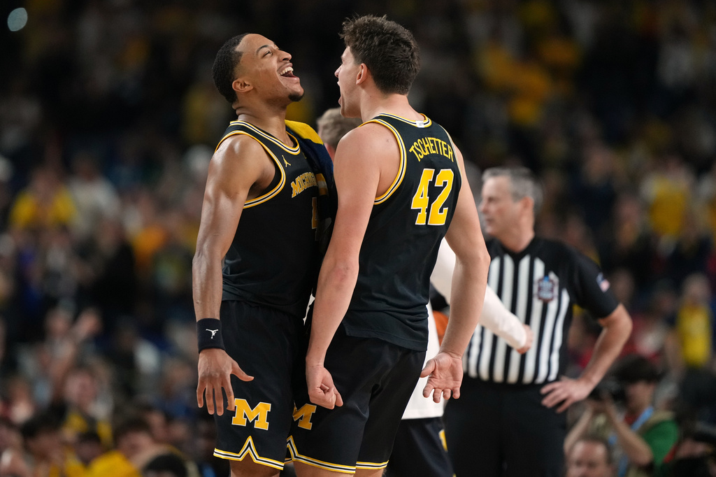 Michigan's Nimari Burnett, left, and Will Tschetter (42) celebrate during the second half of an NCAA college basketball tournament semifinal game against Arizona at the Final Four, Saturday, April 4, 2026, in Indianapolis. (AP Photo/Michael Conroy)