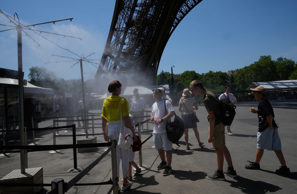 People cool off in a water spray at the Eiffel Tower in Paris, Sunday, June 21, 2026. (AP Photo/Michel Euler)