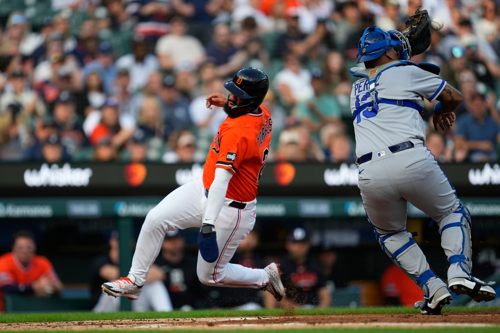 Detroit Tigers' Gleyber Torres, left, runs around Kansas City Royals catcher Salvador Perez (13) to score during the first inning of a baseball game Friday, July 24, 2026, in Detroit. (AP Photo/Paul Sancya)