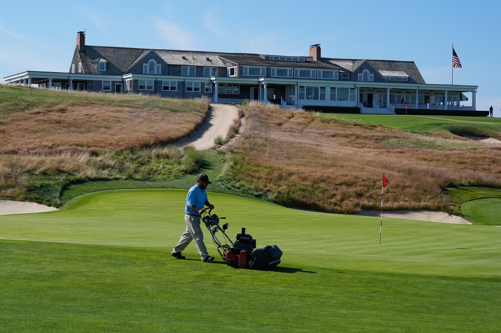 FILE - A man works on the 18th green in front of the clubhouse at Shinnecock Hills Golf Club in Southampton, N.Y., Monday, Sept. 15, 2025. (AP Photo/Seth Wenig, File