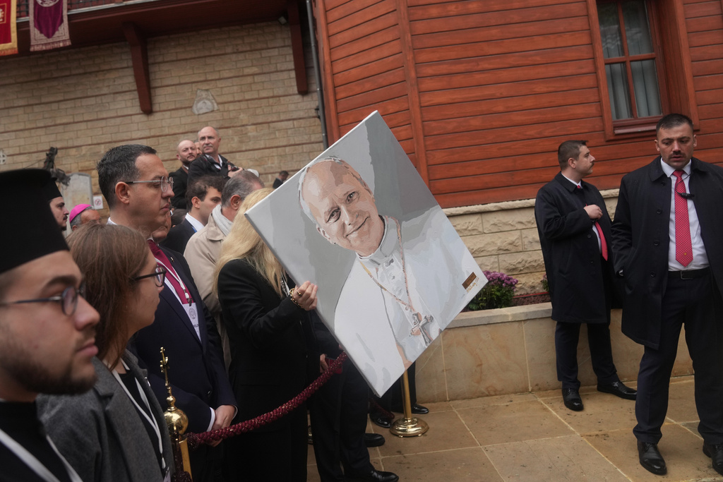 Valerena Yashou holds her painting of the Pope Leo XIV as the crowd wait for him to leave after attending the Doxology with Ecumenical Patriarch Bartholomew I, the spiritual leader of the world's Eastern Orthodox Christians, at the Patriarchal Church of Saint George, in Istanbul, Turkey, Saturday, Nov. 29, 2025. (AP Photo/Francisco Seco)