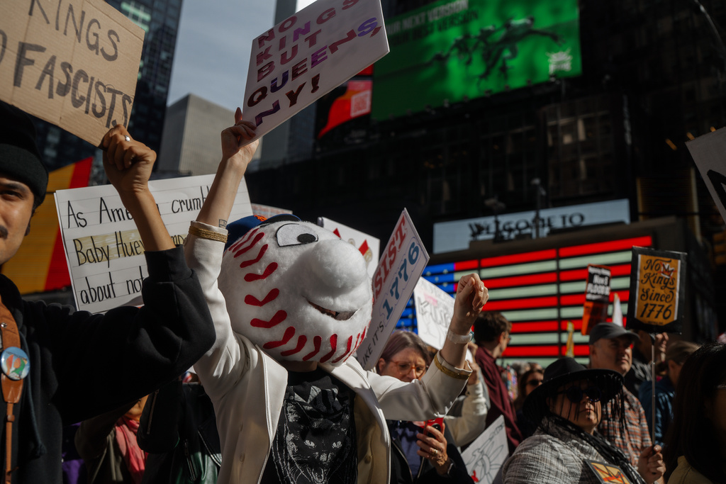 Protester dressed as a baseball mascot holds a sign while marching in Times Square during a "No Kings" protest Saturday, Oct. 18, 2025, in New York. (AP Photo/Olga Fedorova)