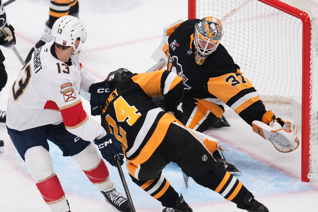 Pittsburgh Penguins goaltender Arturs Silovs (37) reaches to block a shot-attempt by Florida Panthers' Sam Reinhart (13) with Penguins' Spencer Stastney (24) defending during the first period of an NHL hockey game in Pittsburgh, Thursday, Oct. 22, 2026. (AP Photo/Gene J. Puskar)