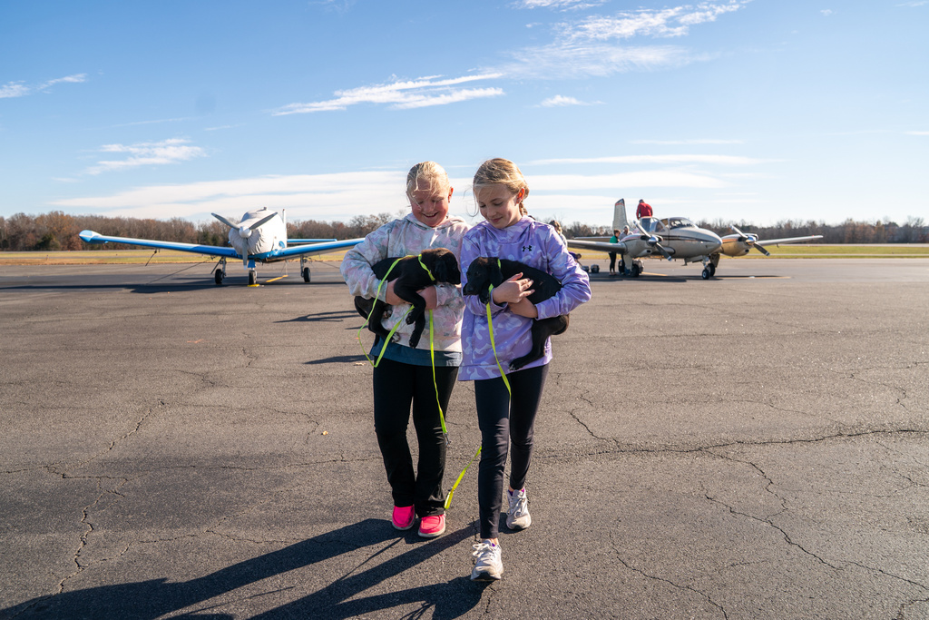 Seuk’s Army volunteers Shelby Campbell, left, and Parker Colbert, carry puppies over to a holding area, after the puppies arrived from overwhelmed Southern animal shelters, at Culpeper Regional Airport in Brandy Station, Va., Nov. 23, 2025. (AP Photo/Allison Robbert)