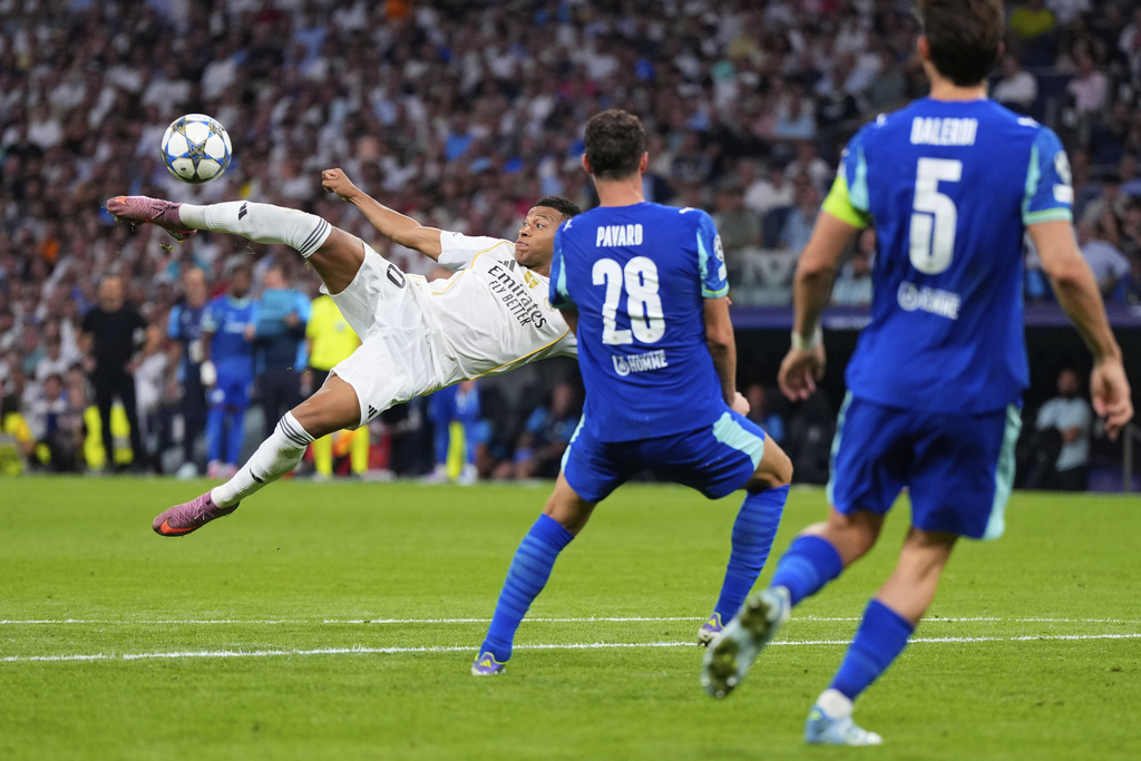 Real Madrid's Kylian Mbappe, left, shoots a high ball next to Marseille defenders during a Champions League opening phase soccer match between Real Madrid and Marseille at Santiago Bernabeu stadium, in Madrid, Tuesday, Sept. 16, 2025. (AP Photo/Manu Fernandez)
