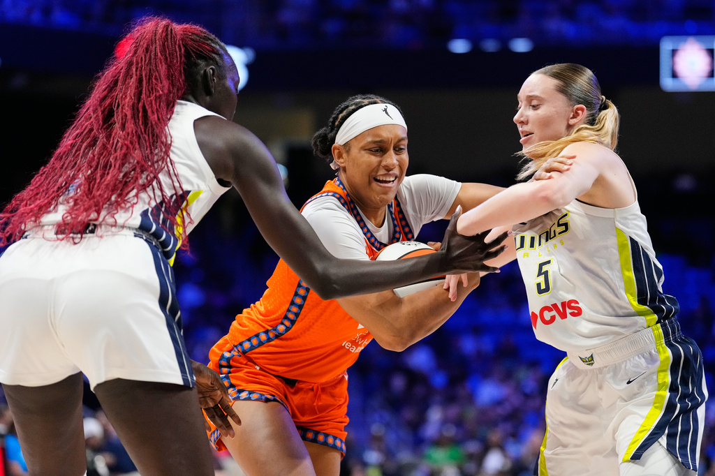 Connecticut Sun's Nell Angloma, center, drives to the basket against Dallas Wings' Awak Kuier, left, and Paige Bueckers (5) during the first half of a WNBA basketball game in Arlington, Texas, Sunday, Aug. 2, 2026. (AP Photo/Tony Gutierrez)