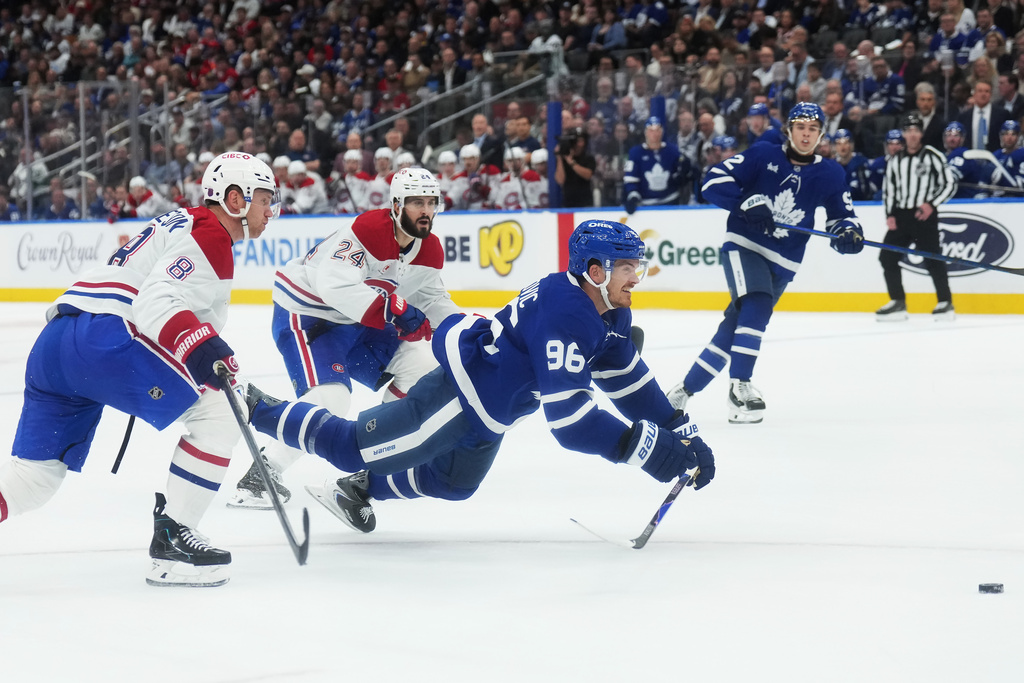 Toronto Maple Leafs' Jack Roslovic (96) gets tripped up by Montreal Canadiens' Mike Matheson (8) and Phillip Danault (24) during the second period of an NHL hockey game against the Montreal Canadiens in Toronto, Tuesday, Sept. 29, 2026. (Nathan Denette/The Canadian Press via AP)
