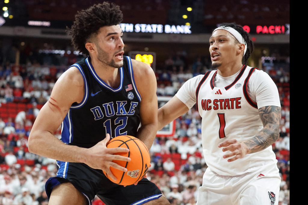 Duke's Cameron Boozer (12) drives the ball past North Carolina State's Darrion Williams (1) during the second half of an NCAA college basketball game in Raleigh, N.C., Monday, March 2, 2026. (AP Photo/Karl DeBlaker)