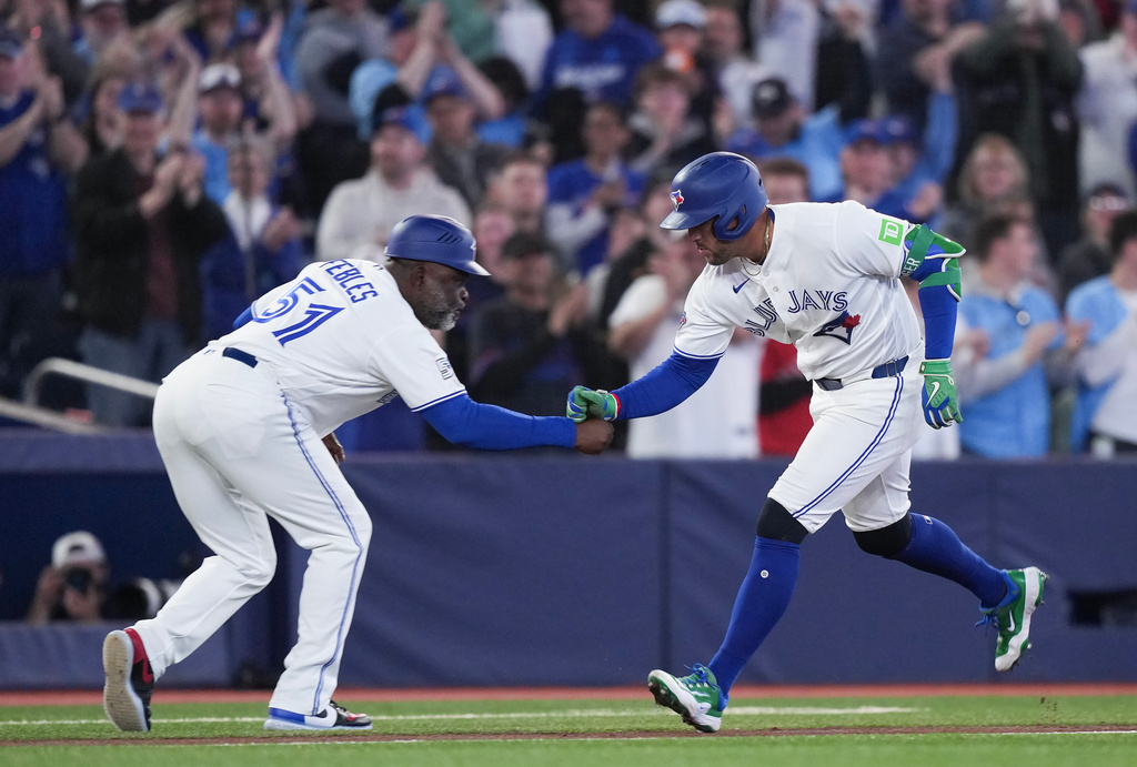 Toronto Blue Jays designated hitter George Springer (4) celebrates his solo home run with Toronto Blue Jays third base coach Carlos Febles (51) while playing against the Athletics during first inning American League baseball action in Toronto on Sunday, March 29, 2026. (Nathan Denette/The Canadian Press via AP)