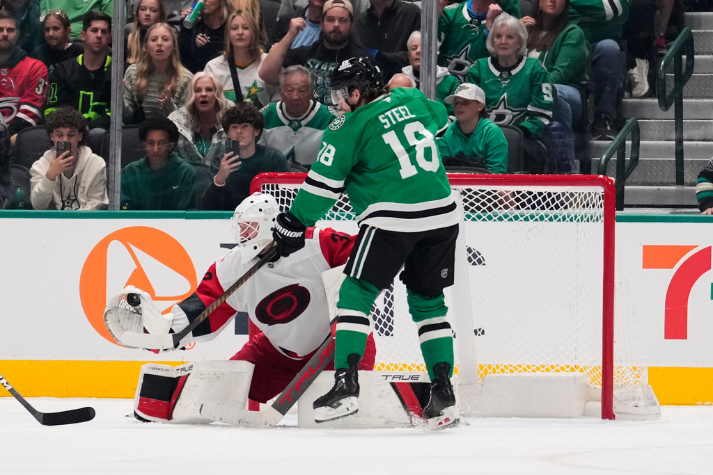 Carolina Hurricanes goaltender Brandon Bussi (32) gloves a shot under pressure from Dallas Stars' Sam Steel (18) in the second period of an NHL hockey game Saturday, Oct. 25, 2025, in Dallas. (AP Photo/Tony Gutierrez)