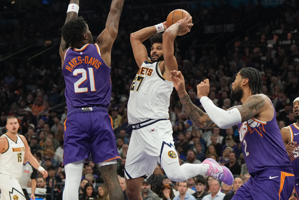 Denver Nuggets guard Jamal Murray (27) drives between Phoenix Suns center Nick Richards (2) and forward Nigel Hayes-Davis (21) during the first half of an NBA basketball game, Saturday, Nov. 29, 2025, in Phoenix. (AP Photo/Rick Scuteri)