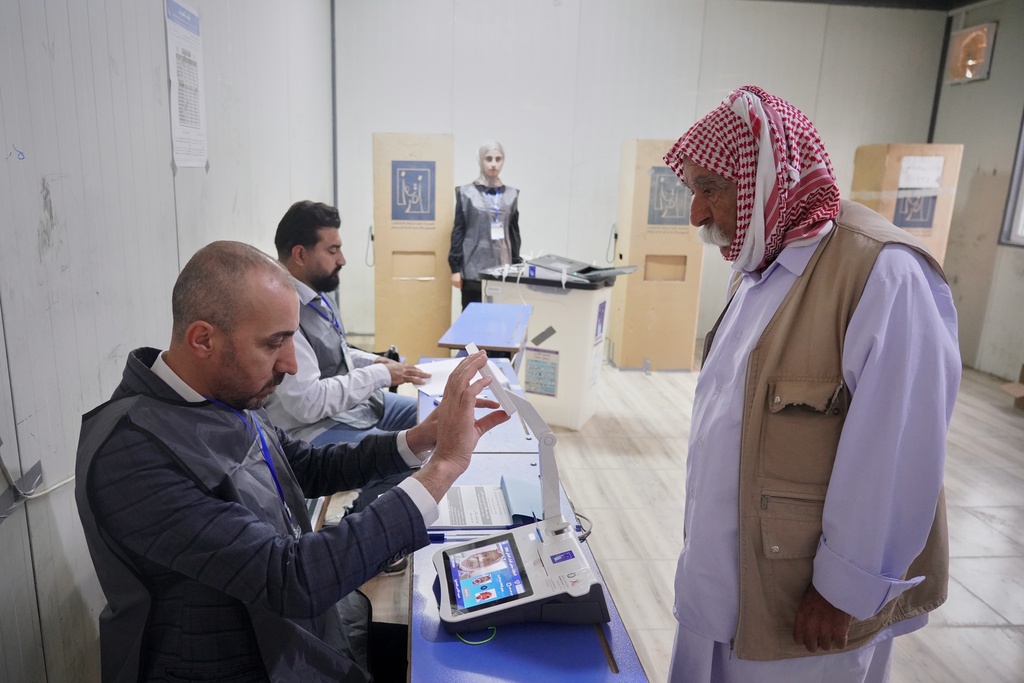A displaced Yazidi man has his fingerprint verified before voting ahead of Iraq's parliamentary elections, set for Nov. 11, at a polling station in the Sharia camp near Dohuk, in Iraq's semi-autonomous Kurdish region, Sunday, Nov. 9, 2025. (AP Photo/Rashid Yahya)