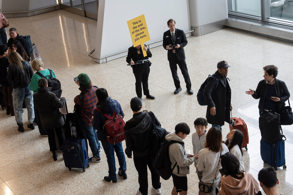 An airport employee holds a sign at the end of a TSA line, Wednesday, March 25, 2026, at LaGuardia Airport in New York. (AP Photo/Yuki Iwamura)