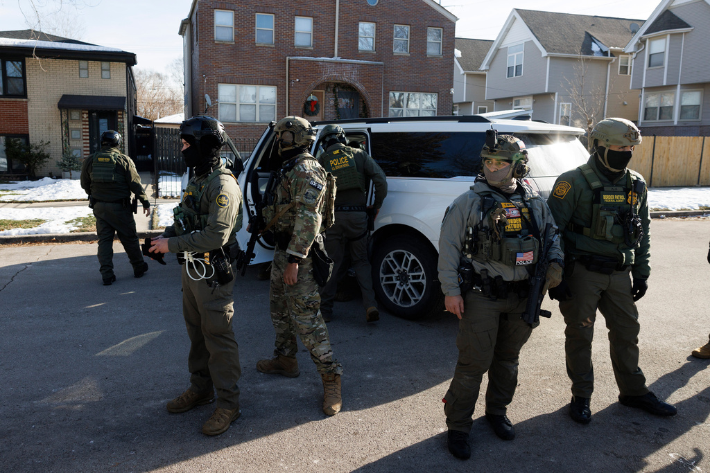 Federal immigration enforcement agents stand guard in front of their vehicles at West 33rd Street and South Ridgeway Avenue in the Little Village neighborhood of Chicago, Tuesday, Dec. 16, 2025. (Anthony Vazquez/Chicago Sun-Times via AP)