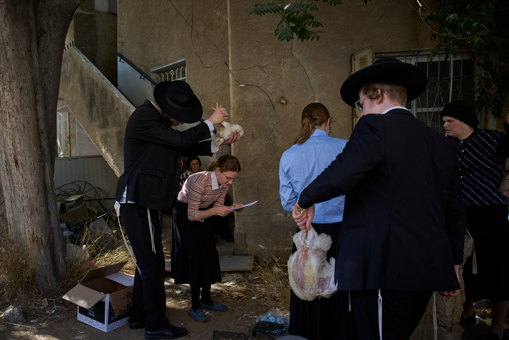 An ultra-Orthodox Jewish man swings a chicken over a woman head in Jerusalem, Monday, Sept. 29, 2025, as part of the Kaparot ritual before the Jewish holiday of Yom Kippur. (AP Photo/Ohad Zwigenberg)