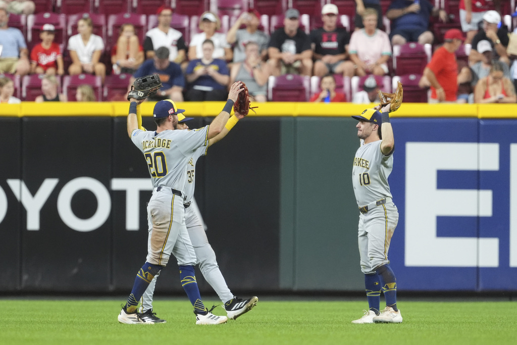 From left, Milwaukee Brewers' Brandon Lockridge, Stewart Berroa and Sal Frelick celebrate their win at the conclusion of a baseball game against the Cincinnati Reds, Friday, Aug. 15, 2025, in Cincinnati. (AP Photo/Kareem Elgazzar)