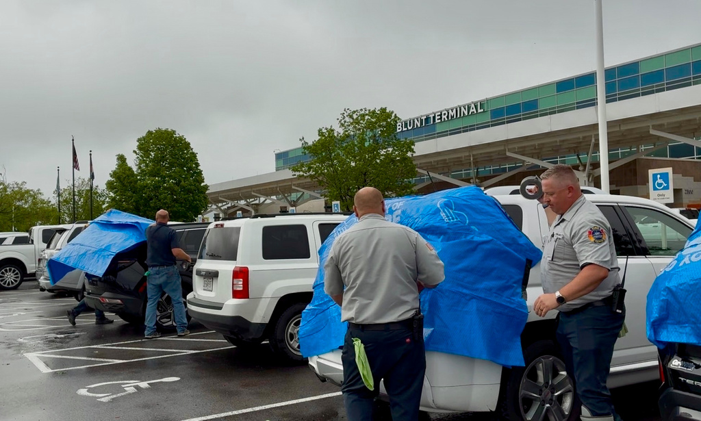 This photo provided by Ren Luebbering shows airport staff placing tarps over cars that were damaged by hail in a parking lot at the Springfield-Branson National Airport in Springfield, Mo., Tuesday, April 28, 2026. (Ren Luebbering via AP)