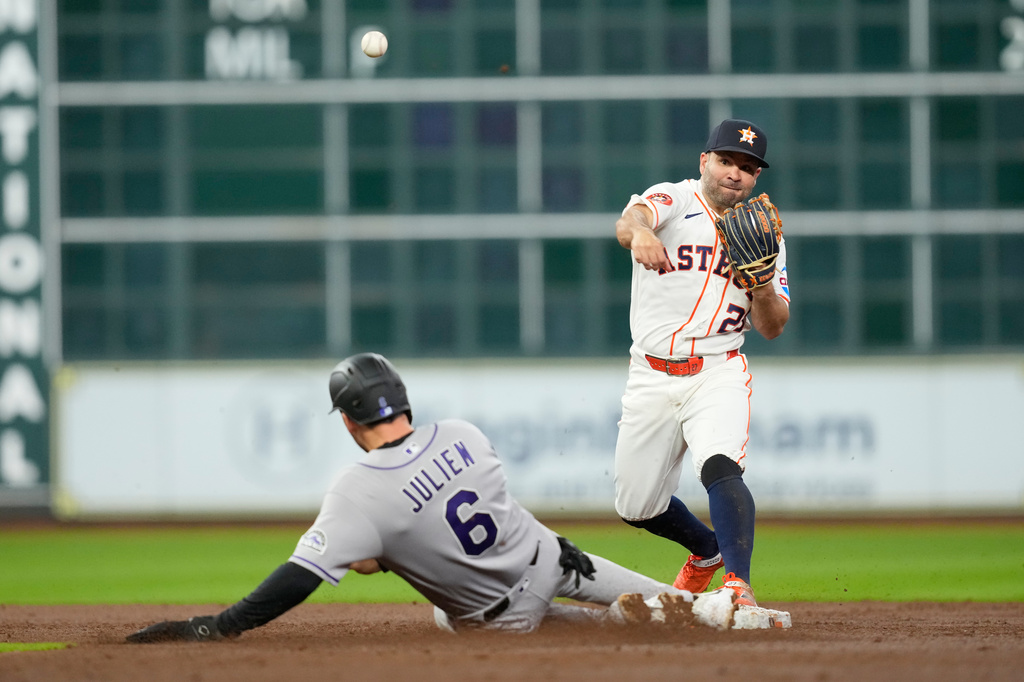 Houston Astros second baseman Jose Altuve (27) turns a double play as Colorado Rockies' Edouard Julien (6) slides into second base during the third inning of a baseball game Thursday, April 16, 2026, in Houston. (AP Photo/David J. Phillip)