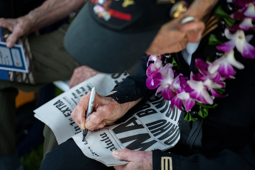 WWII veteran Milton Ripple signs a newspaper before the 84th Pearl Harbor Remembrance Day Ceremony, Sunday, Dec. 7, 2025, in Honolulu. (AP Photo/Mengshin Lin)