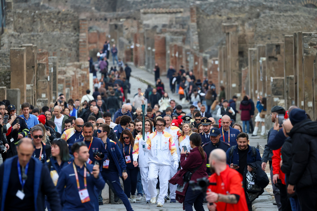 Actor Jackie Chan holds the olympic torch passing through the Archaeological Park in Pompeii, Italy, Monday, Dec. 22, 2025. (Alessandro Garofalo/LaPresse via AP)