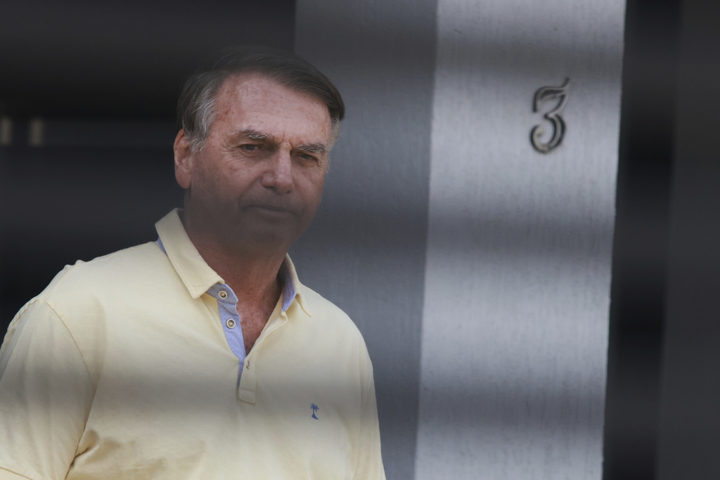 Brazil's former President Jair Bolsonaro stands behind the entrance gate of his home where he is under house arrest in Brasilia, Brazil, Wednesday, Sept. 3, 2025. (AP Photo/Luis Nova)