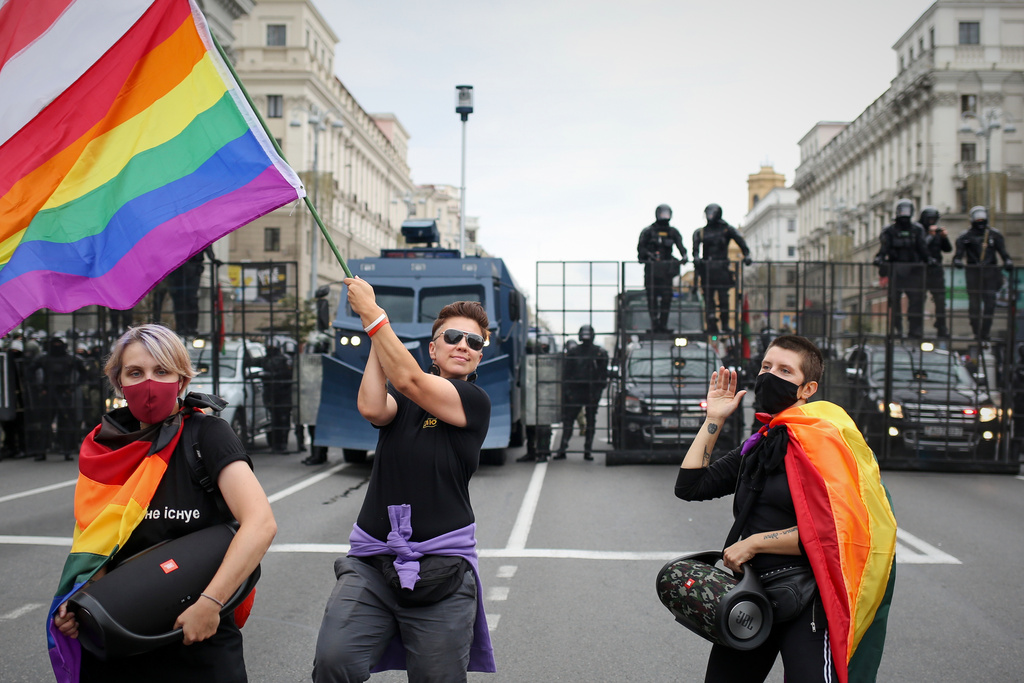 FILE - LGBT activists perform with rainbow flags and an old Belarusian national flag, in front of a police barricade blocking a street during an opposition rally to protest the official presidential election results in Minsk, Belarus, Sunday, Sept. 6, 2020. (AP Photo, File)