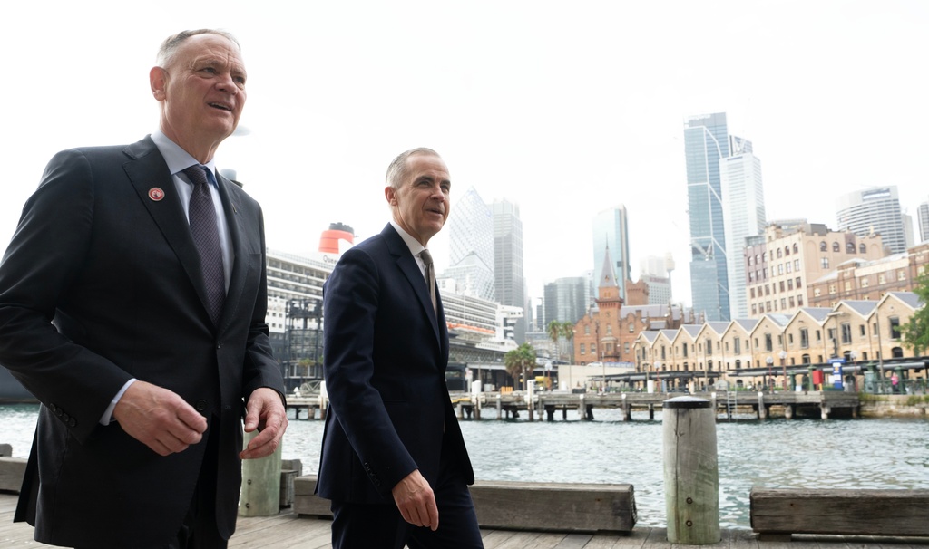 Canadian Defence Minister David McGuinty talks with Canadian Prime Minister Mark Carney as they walk to a news conference in Sydney, Australia, Wednesday, March 4, 2026 in Sydney. (Adrian Wyld/The Canadian Press via AP)
