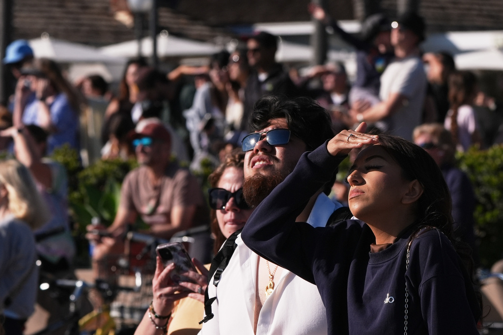 People wait for a glimpse of the return of NASA's Artemis II Friday, April 10, 2026, along the beach in Coronado, Calif. (AP Photo/Gregory Bull)