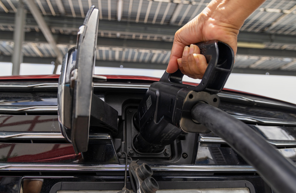 A driver plugs in her Chinese-made MG electric vehicle to charge at a parking lot in Bangkok, Thailand on June 4, 2026. (AP Photo/Anton L. Delgado)