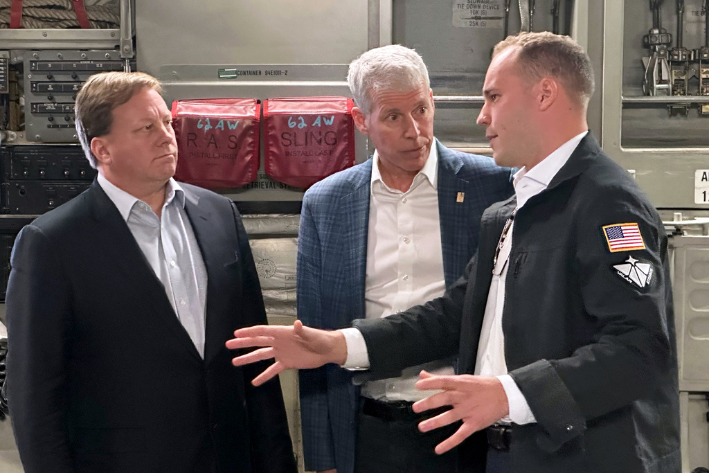 Energy Secretary Chris Wright, center, and Under Secretary of Defense Michael Duffey, left, listen as Isaiah Taylor, CEO of Valar Atomics, discusses a microreactor developed by Valar to generate nuclear power for the military and commercial customers, Sunday, Feb. 15, 2026, in-flight, on board a C-17. (AP Photo/Matthew Daly)