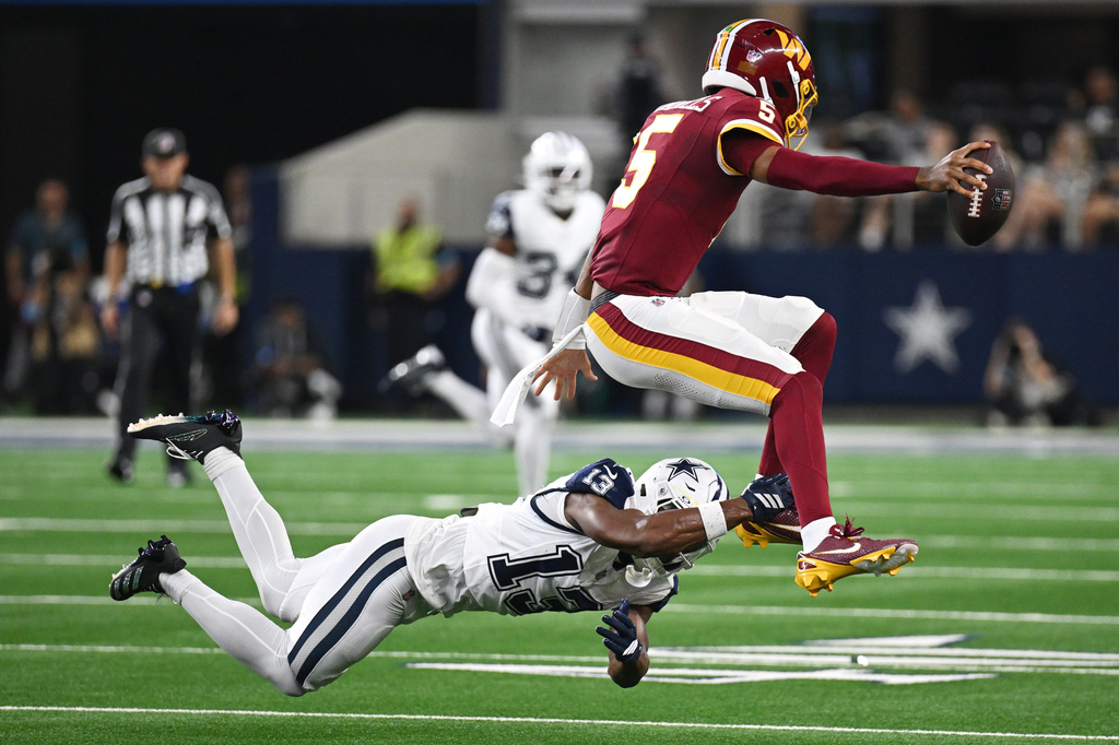 Dallas Cowboys safety Caleb Downs (13) tackles Washington Commanders quarterback Jayden Daniels (5) in the first half during an NFL football game in Arlington, Texas, Sunday, Sept. 20, 2026. (AP Photo/Jessica Tobias)