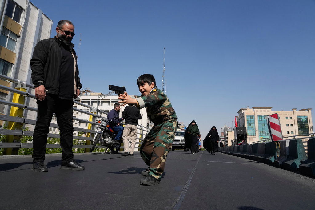 A boy plays with a toy gun on the sidelines of a state-organized rally supporting the supreme leader, marking National Girls' Day, in Tehran, Iran, Friday, April 17, 2026. (AP Photo/Vahid Salemi)