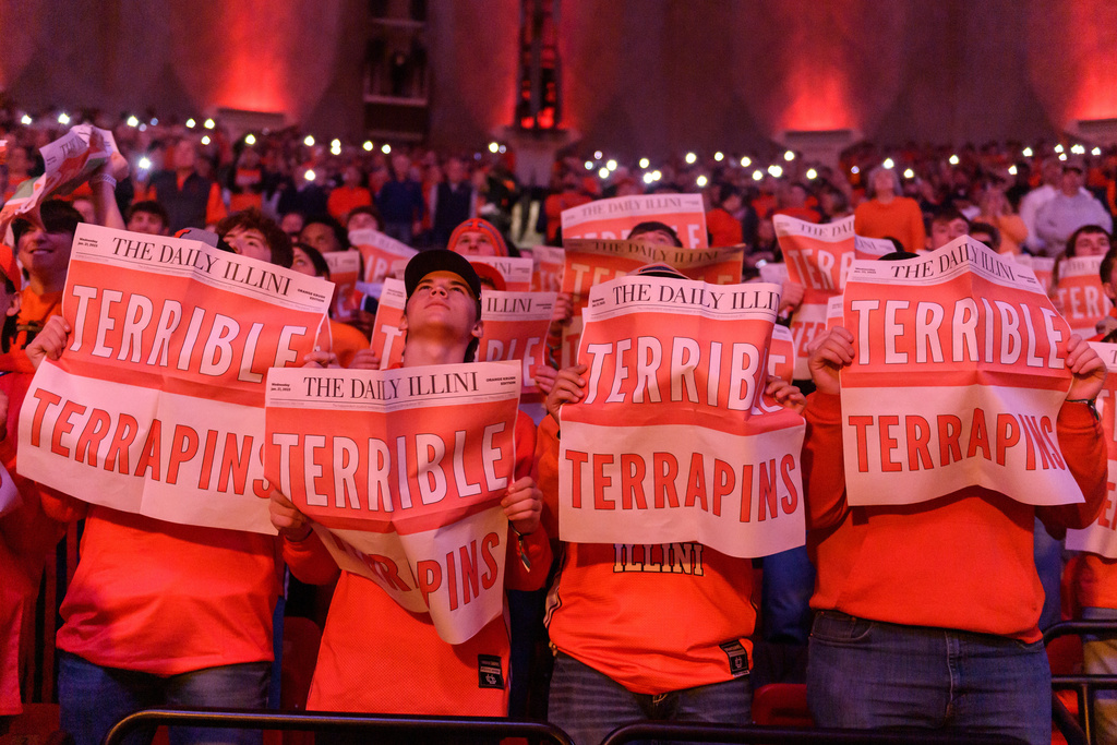 Members of the Orange Krush student section hold up faux newspapers before an NCAA college basketball game against Maryland, Wednesday, Jan. 21, 2026, in Champaign, Ill. (AP Photo/Craig Pessman)