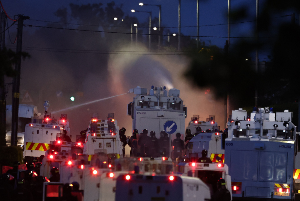 Police fire a water cannon towards rioters after they set fire to wheelie bins and removed a garden fence to use as a shield against the water cannon in Newtownabbey, Belfast, Northern Ireland, Wednesday June 10, 2026. (PA via AP)