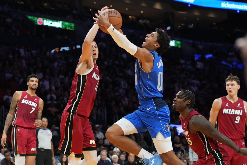 Miami Heat guard Tyler Herro (14) blocks a drive to the basket by Dallas Mavericks guard Max Christie (00) during the first half of an NBA basketball game Monday, Nov. 24, 2025, in Miami. (AP Photo/Marta Lavandier)