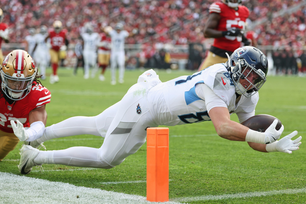 Tennessee Titans tight end Gunnar Helm (84) dives for a touchdown past San Francisco 49ers safety Ji'Ayir Brown, left, during the first half of an NFL football game, Sunday, Dec. 14, 2025, in Santa Clara, Calif. (AP Photo/Jed Jacobsohn)